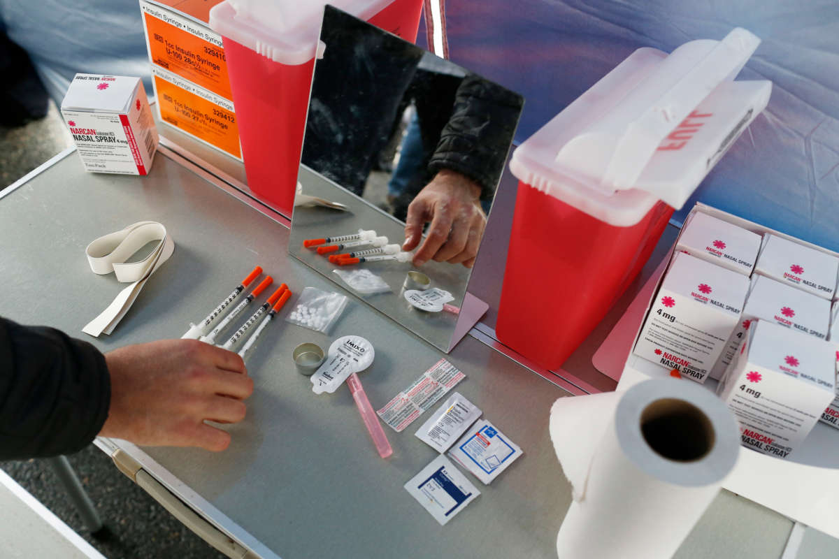 A visitor to a mock safe injection site set up by SIF MA NOW at Harvard School of Public Health checks out the items on the demonstration table near the medical school in Boston, Massachusetts, on April 30, 2018.