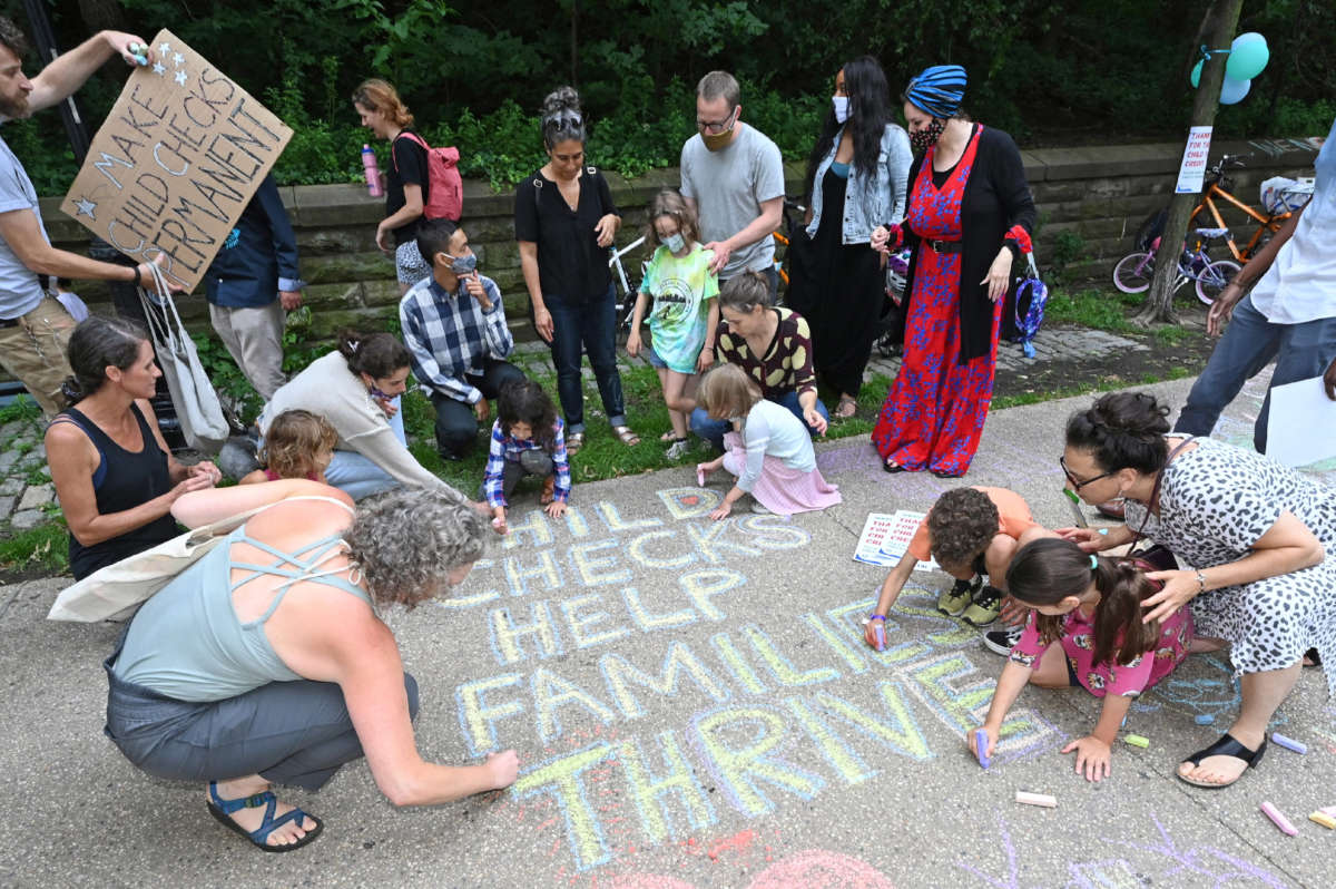Parents and children celebrate new monthly Child Tax Credit payments and urge congress to make them permanent outside Sen. Chuck Schumer's home on July 12, 2021, in Brooklyn, New York.
