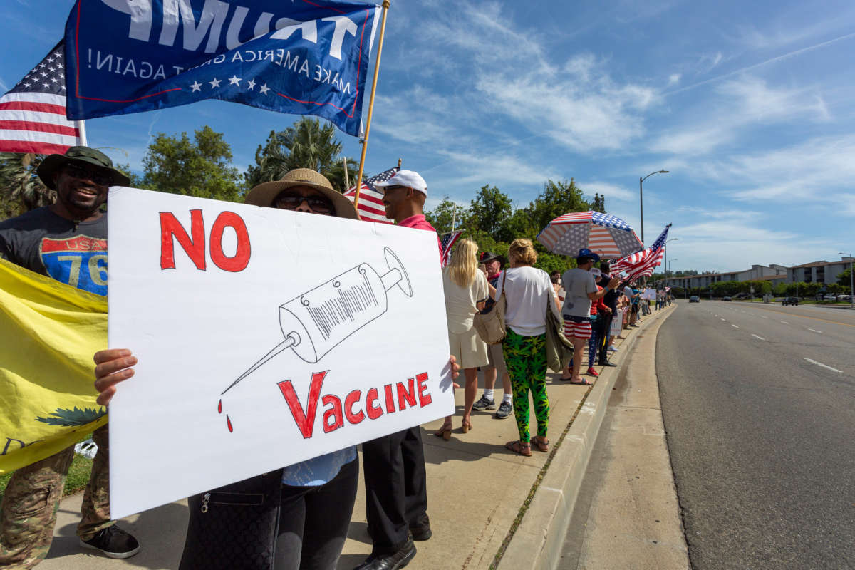 A protester holds an anti-vaccination sign as Trump supporters rally on May 16, 2020, in Woodland Hills, California.