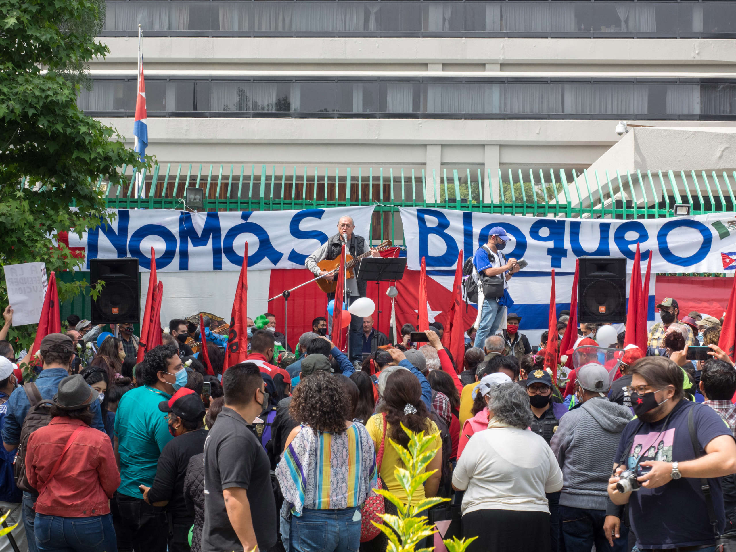 An artist performs a song for the crowd at the Cuban embassy in Mexico in front of a banner that reads "No More Blockade" on July 17, 2021.