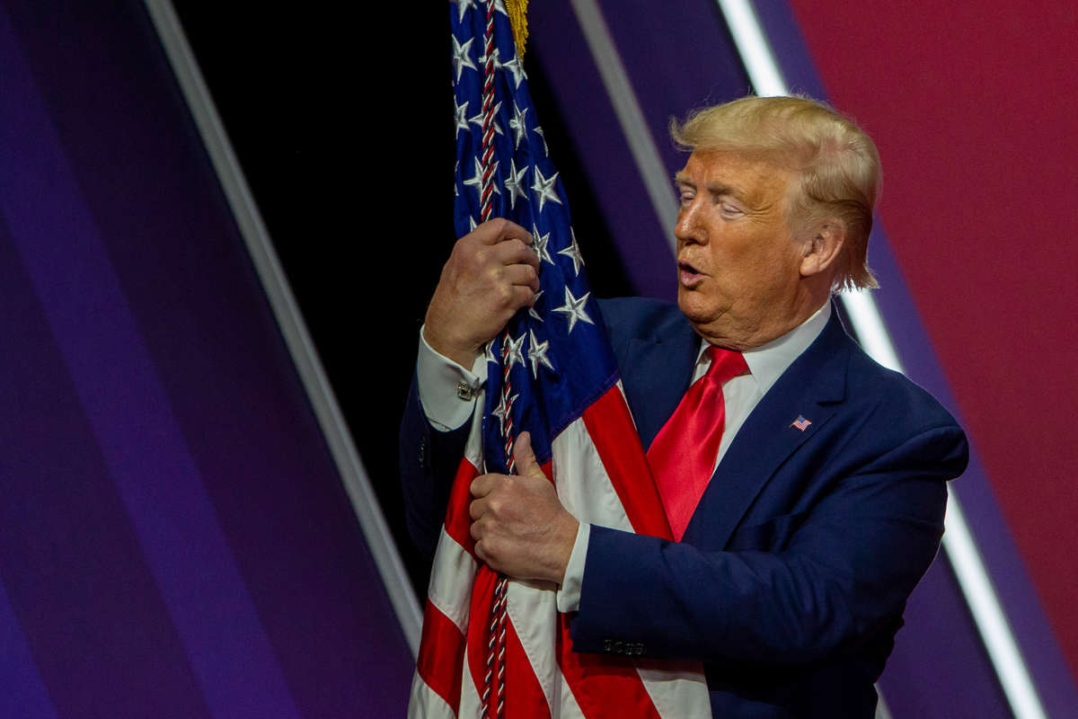 President Donald Trump hugs the flag of the United States of America at the annual Conservative Political Action Conference at Gaylord National Resort & Convention Center February 29, 2020, in National Harbor, Maryland.