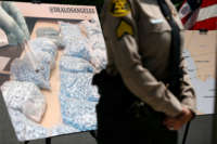 An officer stands in front of a displayed photograph showing counterfeit fentanyl pills during a press conference on May 13, 2021, in Los Angeles, California.