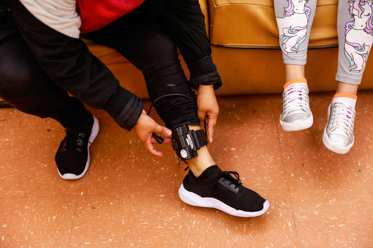 Faustina Alvarado Garcia (left) sits next to her daughter Madelin Souza Alvarado, 11, as she adjusts her ankle monitor in the community room at Hamilton shelter in San Francisco, California, on June 18, 2019. Her ankle monitor was put on her by immigration and has been causing her pain.
