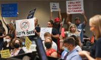 People demonstrate with placards at an emergency meeting of the Brevard County, Florida School Board in Viera to discuss whether face masks in local schools should be mandatory, on August 30, 2021.