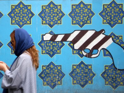 A woman passes a mural painted on the wall of the former US Embassy in Tehran, Iran.
