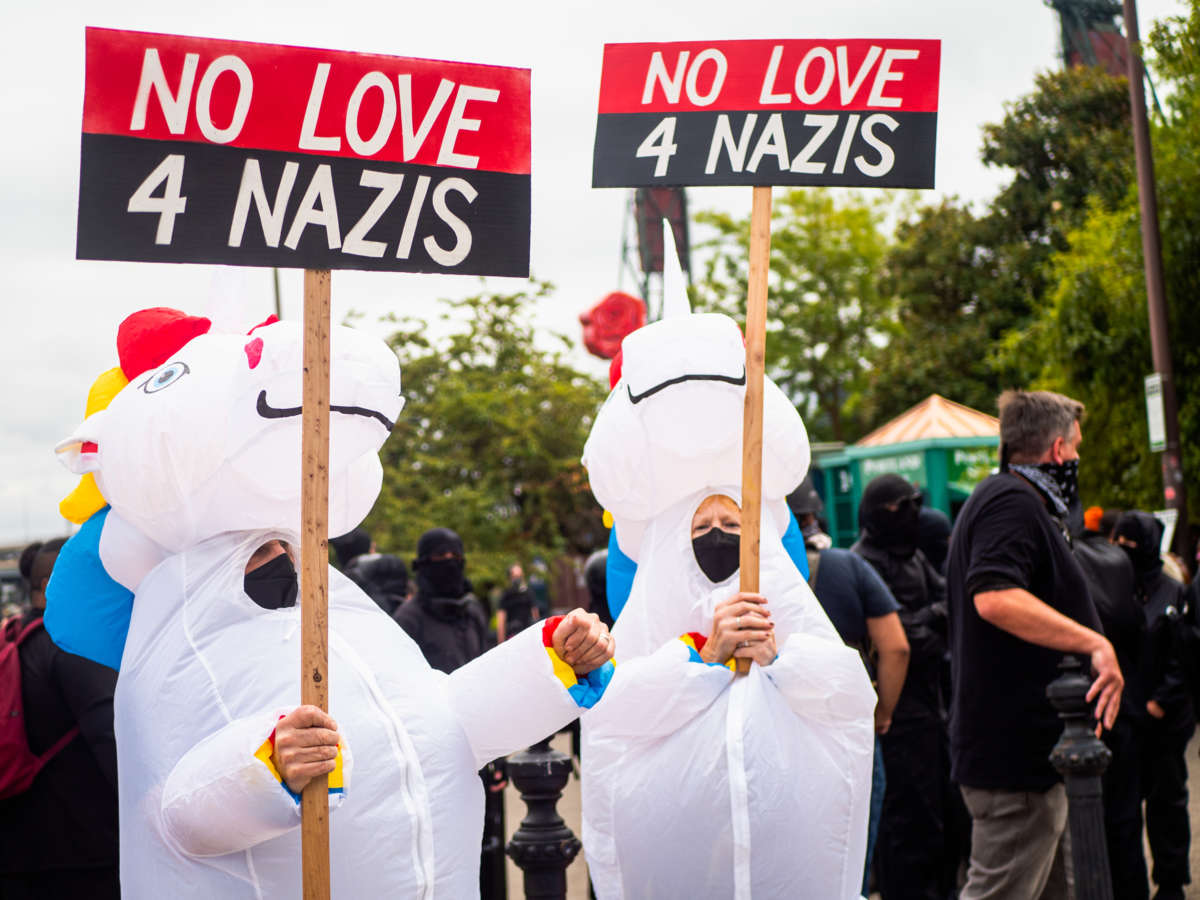 Protesters in unicorn costumes display signs reading "NO LOVE 4 NAZIS" during a protest