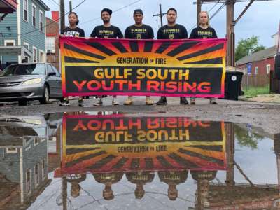 Sunrise Movement marchers Chanté Davis, Joshua Benitez, Rogelio Meixueiro, Javier Enriquez and Hope Endrenyi stand with their hand-painted banner on a street in Central City, New Orleans, shortly before the launch of the march.