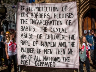Protesters hold signs at a rally to demand all asylum seekers and refugees be brought to Australia following the Papua New Guinea government's decision to close its refugee camp. In August, leaked Nauru files made shocking revelations regarding child abuse at the Nauru detention center.