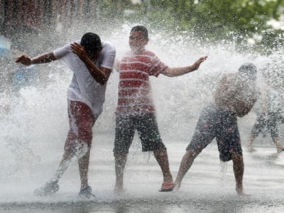 Children play in water sprayed from a fire hydrant during an early summer heat wave in the Bronx borough of New York City.