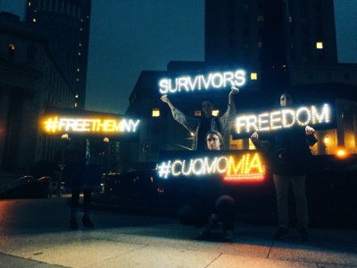 Two days before the primary, Survived and Punished members lift lighted messages demanding Gov. Andrew Cuomo commute the sentences of criminalized survivors.