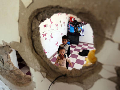 Displaced Yemeni children from the Hodeidah province are pictured on September 30, 2018, through a hole in a damaged house where they have been living with other displaced families in the southwestern Yemeni city of Taez. The conflict has triggered what the UN describes as the world's worst humanitarian crisis, with 22 million people in need of humanitarian aid.