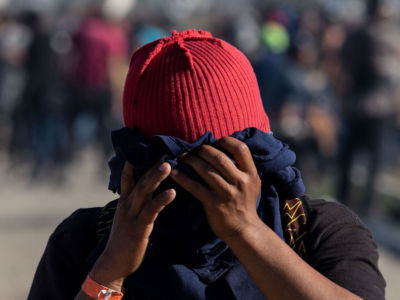 A Central American migrant covers his face near the El Chaparral border crossing in Tijuana, Baja California State, Mexico, after the US Border Patrol threw tear gas to disperse a crowd on November 25, 2018.