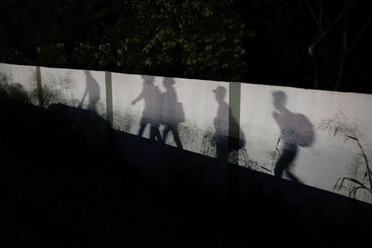 Shadows are reflected on a wall as members of the Central American migrant caravan moves in the pre-dawn hours on November 2, 2018, in Matias Romero, Mexico.