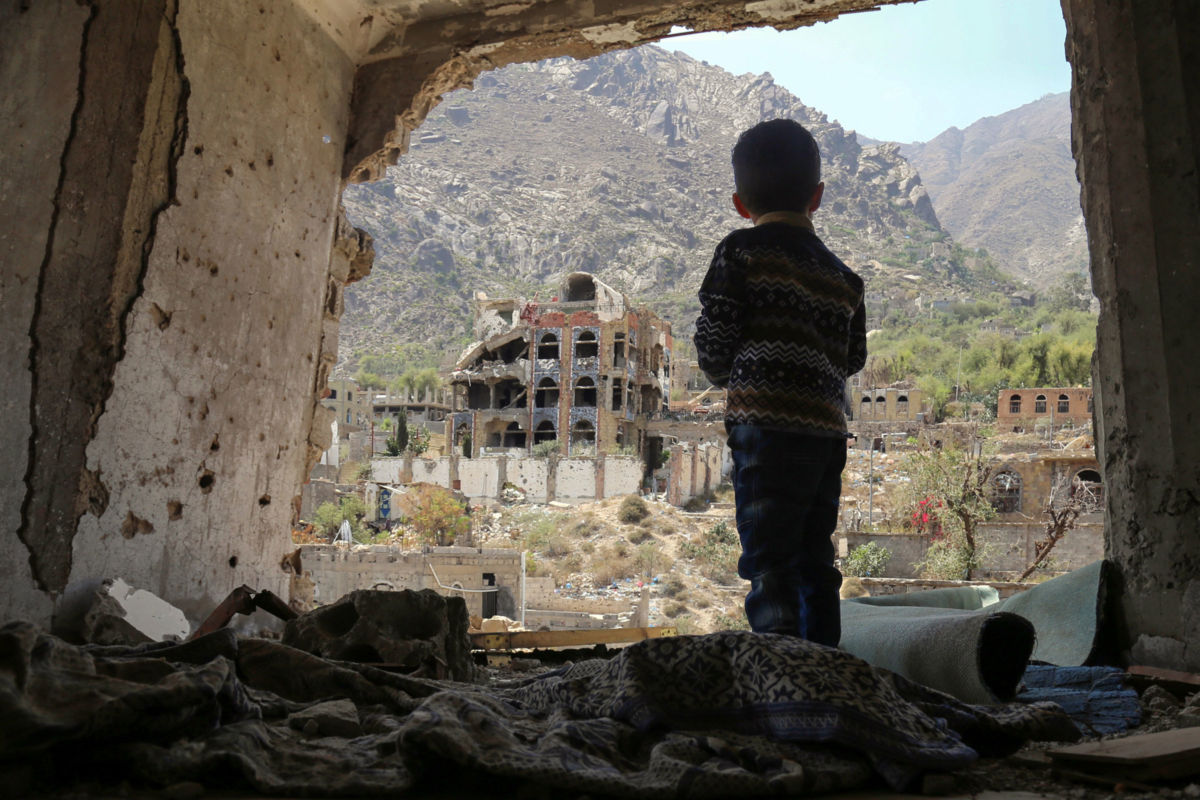 A Yemeni child looks out at buildings that were damaged in an air strike in the southern Yemeni city of Taez, March 18, 2018.