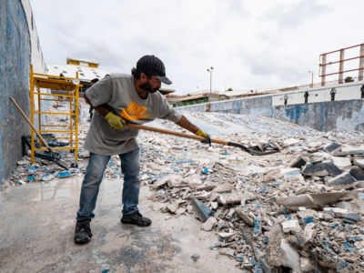 Workers shovel debris from the swimming and diving pool in the Aquatic Center at the Albergue Olympic Training Center of Puerto Rico on November 14, 2018, in Salinas, Puerto Rico.