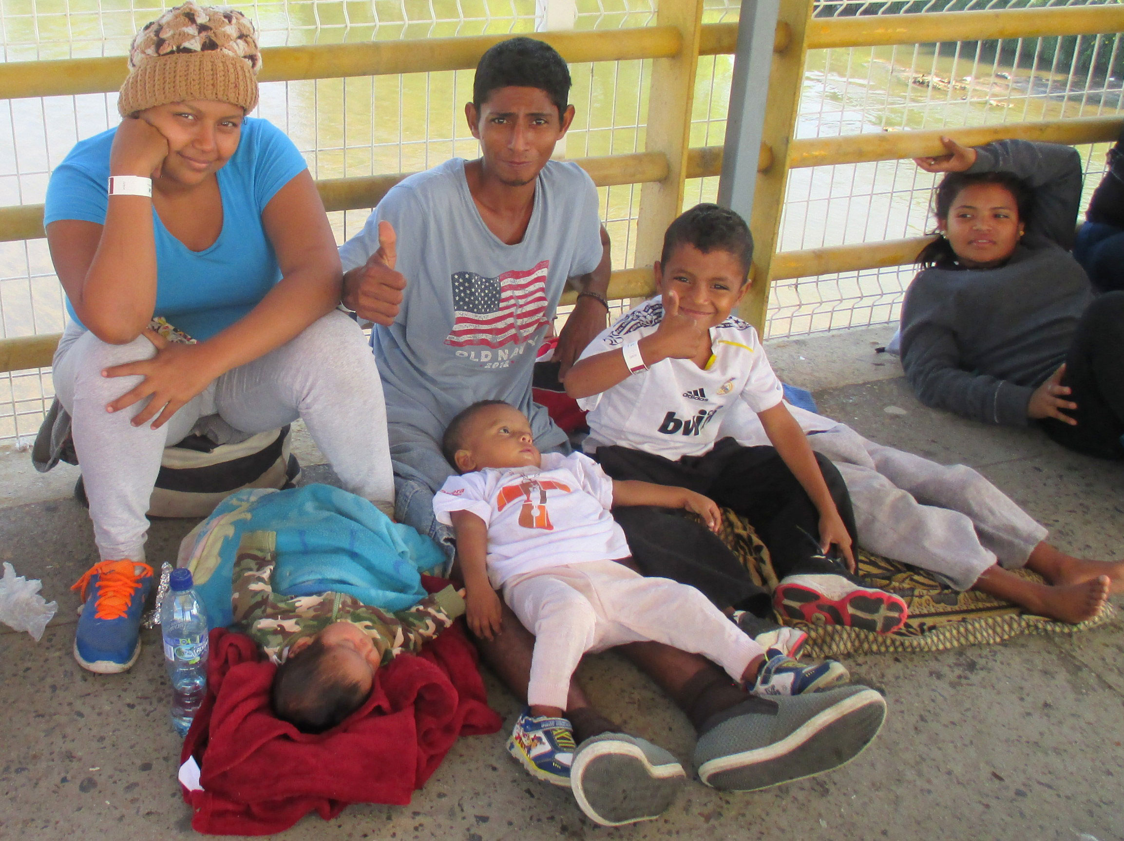 A Honduran family sits on the bridge over the Suchiate River in January 2019, waiting for the line to advance towards the Mexican immigration offices.