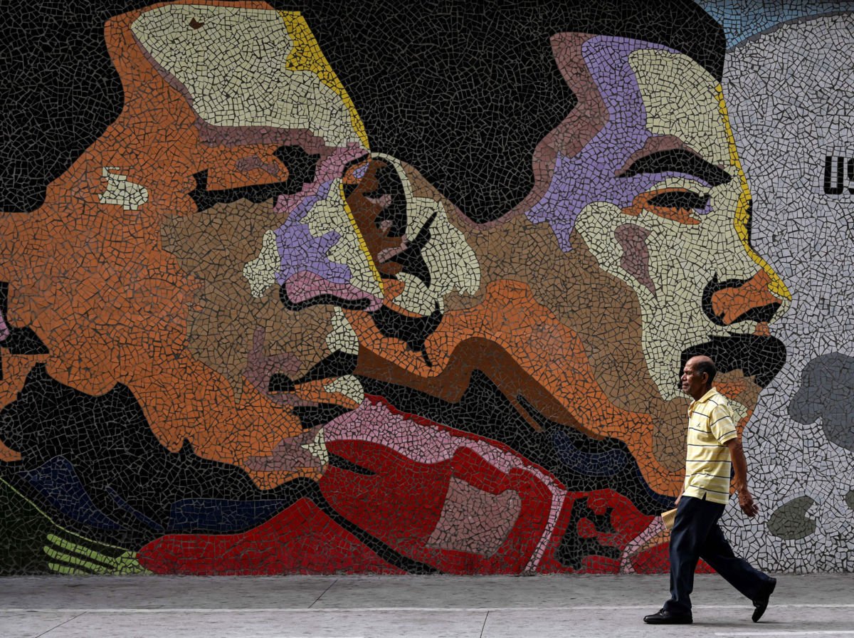 A man walks past a mosaic depicting late Venezuelan President Hugo Chavez (L) and Venezuelan president Nicolas Maduro on a wall in Caracas on January 30, 2019.