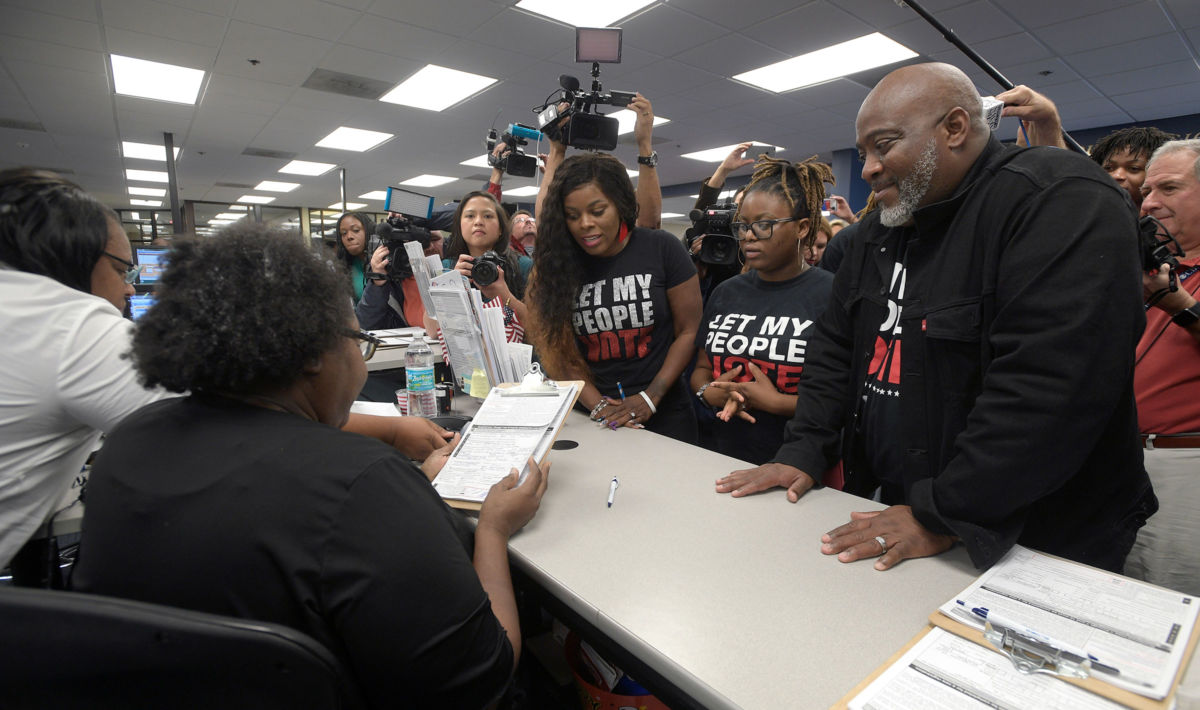﻿A man with his family registers to vote after ex-felons regained voting rights in Florida.