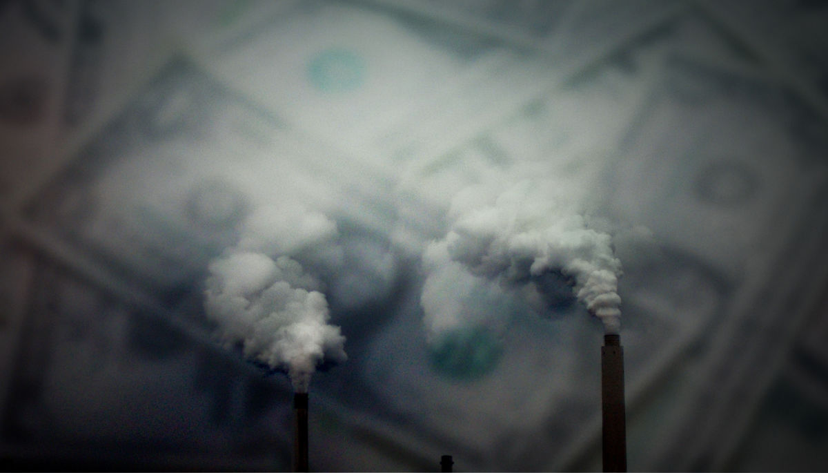 Two smokestacks billow smoke into a hazy gray sky with U.S. dollars in the background