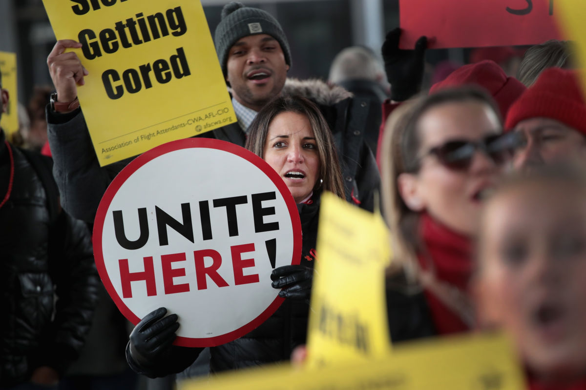 A woman holds a sign that reads "UNITE HERE" during a protest