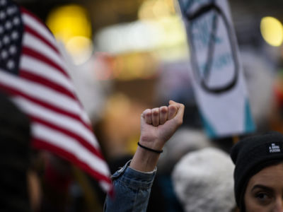 A woman raises a fist in the midst of a protest