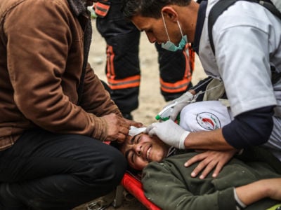 Palestinian medical staff treat an injured youth during a protest at the Israel-Gaza border