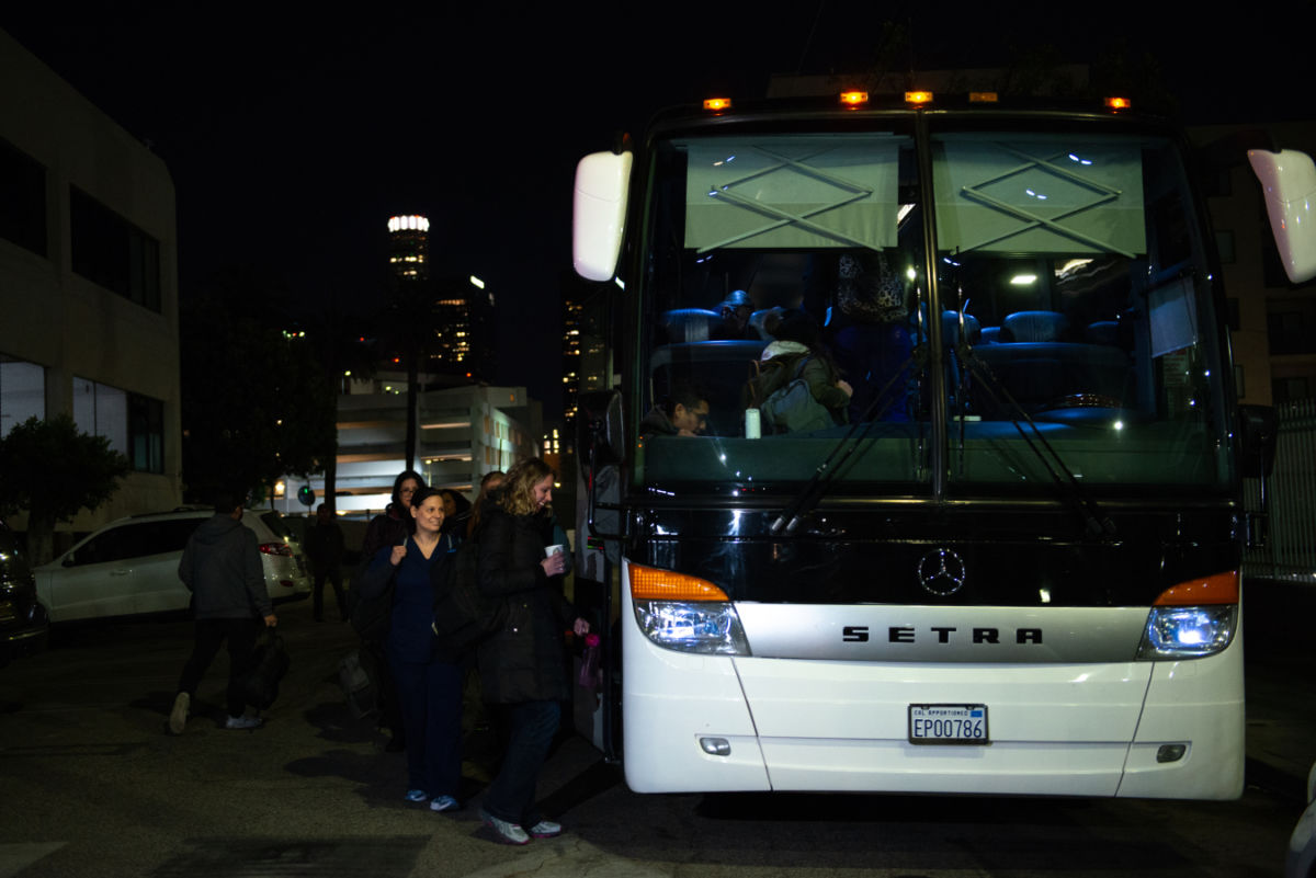 People board a bus at nighttime