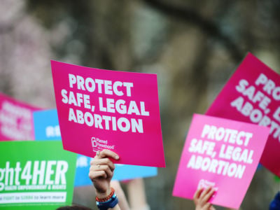 People raise signs reading Protect Safe, Legal Abortion at a pro-choice rally