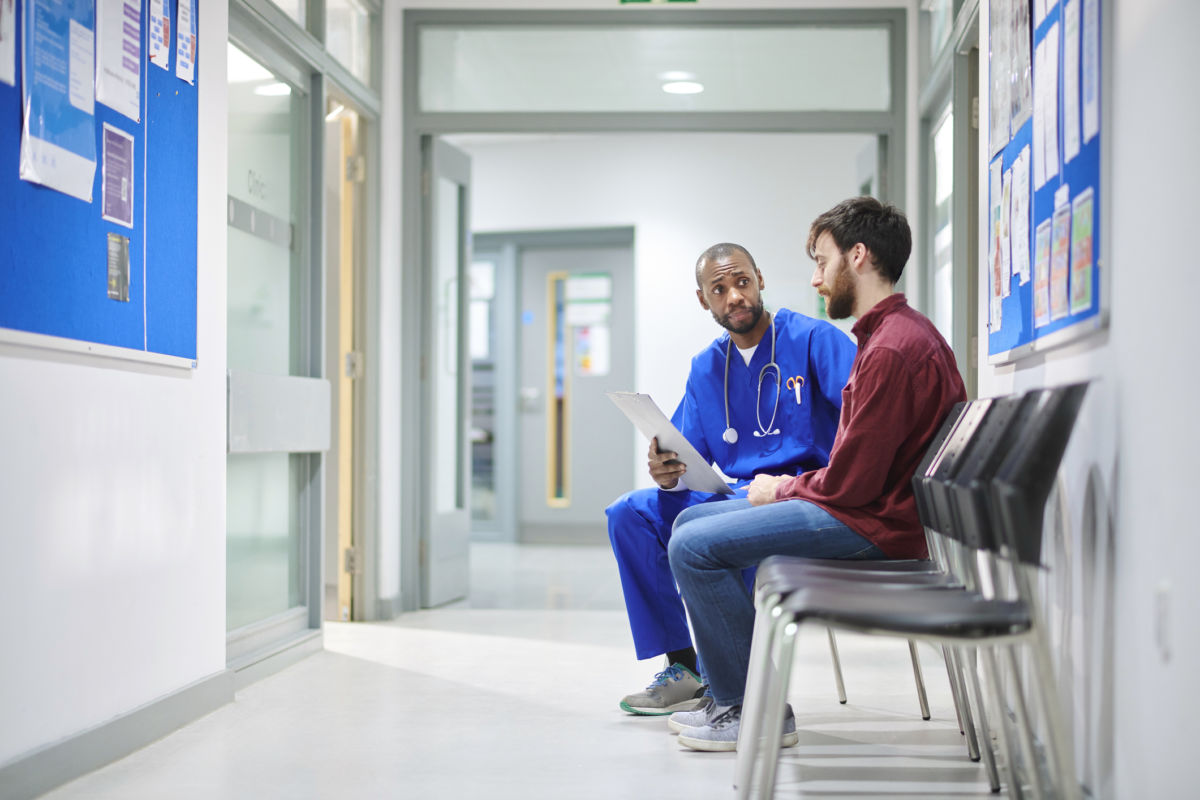A doctor talks to a patient in a hospital waiting room