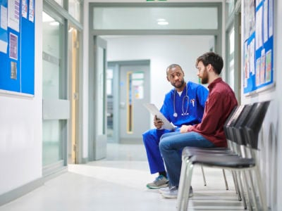 A doctor talks to a patient in a hospital waiting room