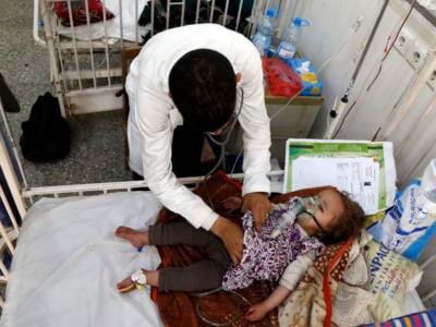 a little girl recieves care from a doctor while lying in a hospital bed
