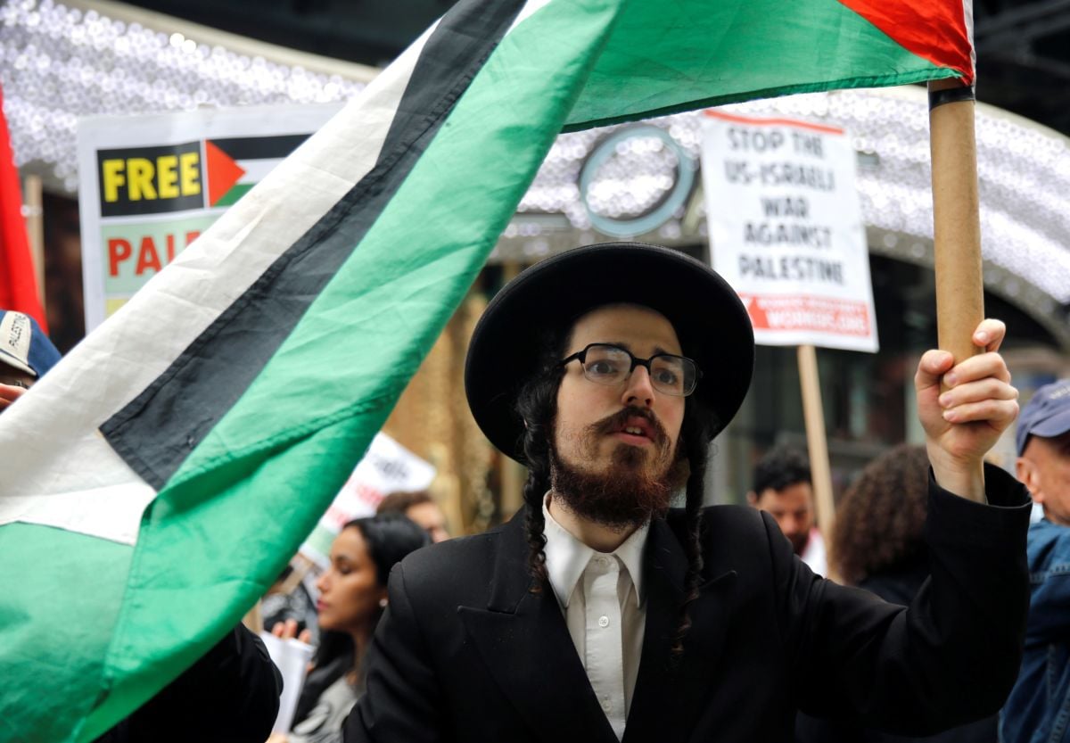 A Jewish man holds a Palestinian flag during a rally