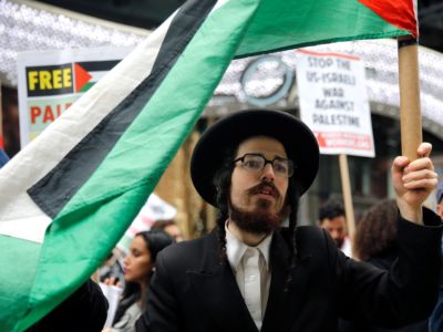 A Jewish man holds a Palestinian flag during a rally