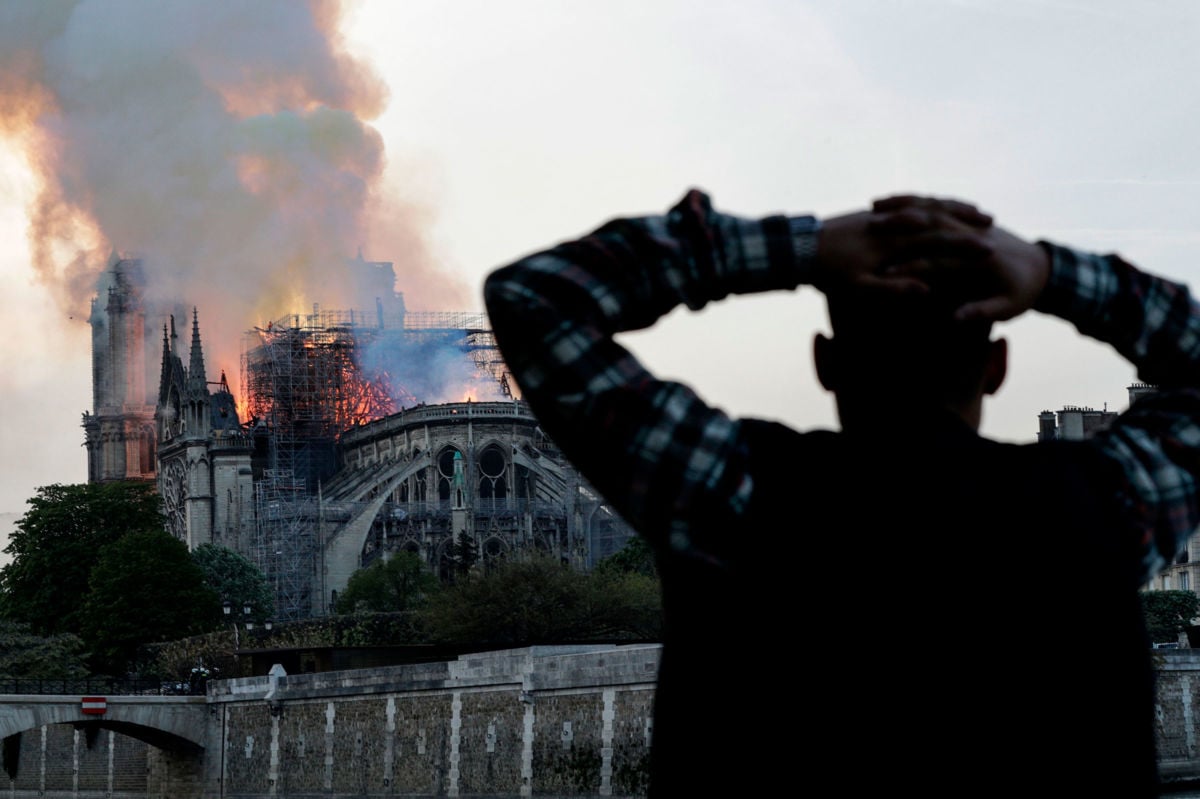 A man watches the landmark Notre Dame Cathedral burn in central Paris on April 15, 2019.