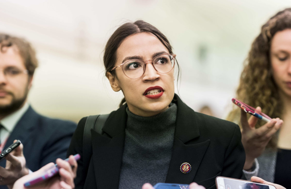 AOC looks stern as questioned by reporters holding cell phones