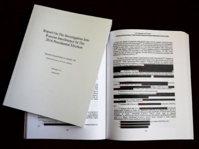 Pages of the redacted Mueller report sit open on a desk
