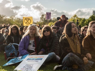 Activists listen to speeches and songs through a small PA system in Hyde Park at the closing ceremony of the Extinction Rebellion protest on April 25, 2019, in London, England.