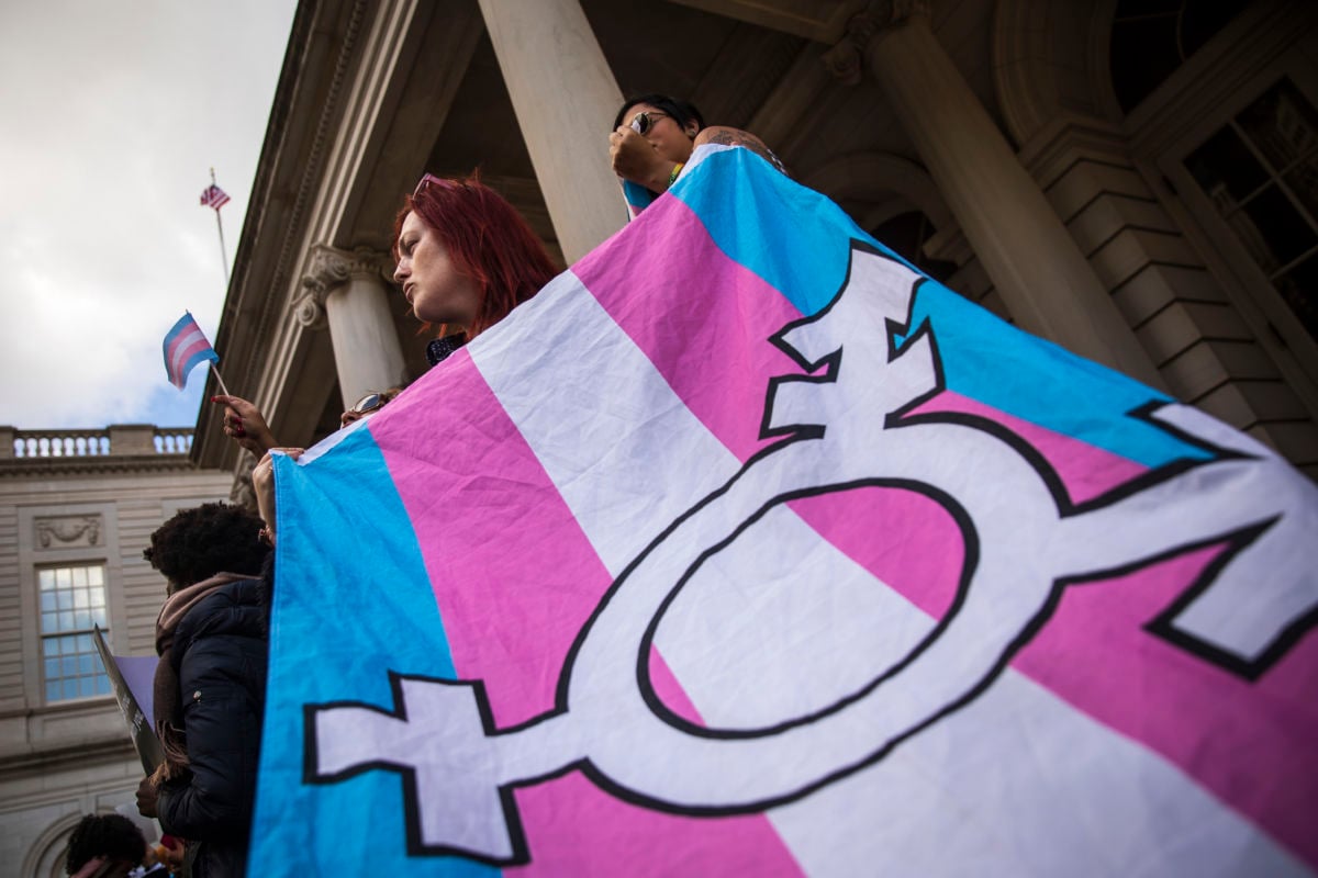A woman holds the trans flag during a protest
