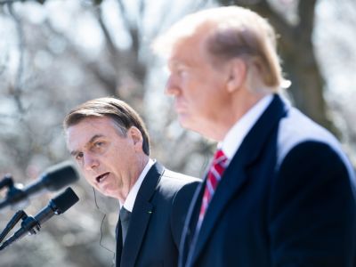 Jair Bolsonaro speaks into a microphone while Donald Trump stands in the foreground