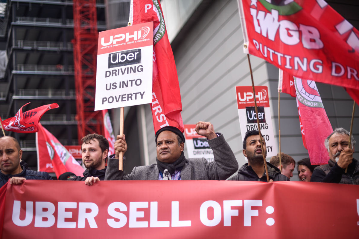 People in red protest Uber while holding pro-union signs