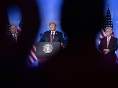 Mike Pompeo, Donald Trump and John Bolton stand on a stage