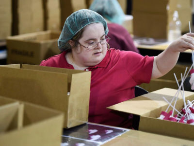 A woman repackages plastic sprayers at a sheltered workshop for adults with disabilities.