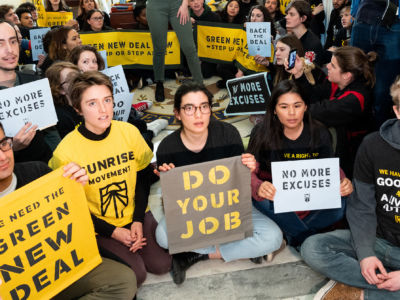 Protesters seen holding placards during the Sunrise Movement protest inside the office of US Representative Nancy Pelosi to advocate that Democrats support the Green New Deal, at the U.S. Capitol in Washington, D.C.