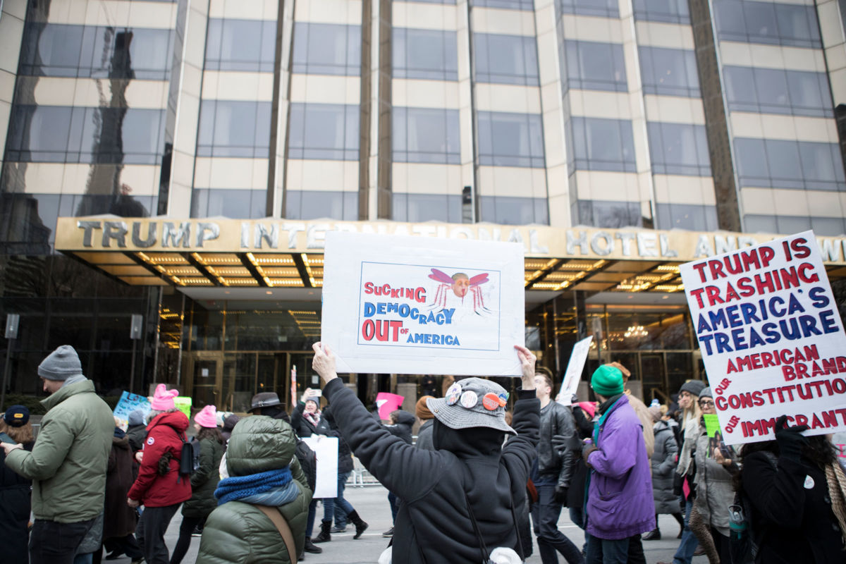 A marcher holds a sign that say, "Sucking Democracy Out of America" with an image of Donald Trump as a mosquito in front of Trump International Hotel during the Woman's March in the borough of Manhattan in New York on January 19, 2019.