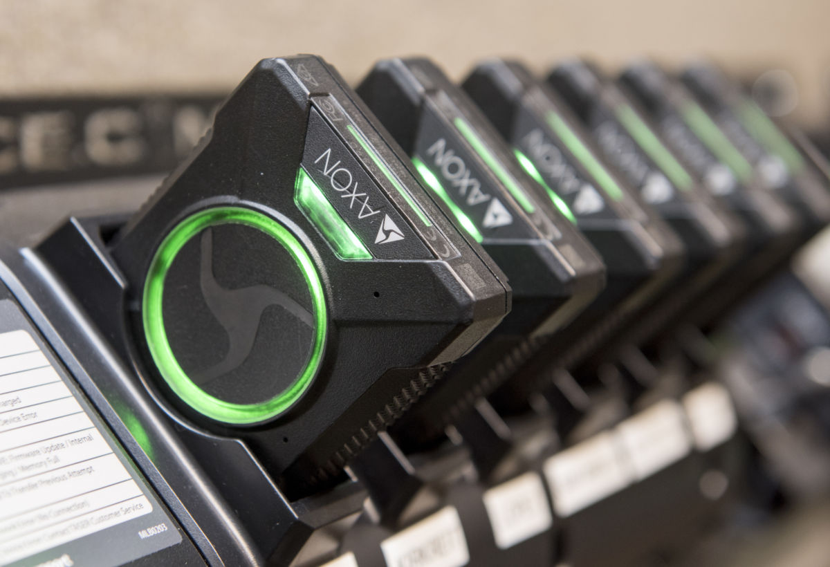 A line of body cameras charge in a charging port
