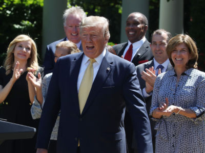 Donald Trump walks toward a podium as people beghind him clap