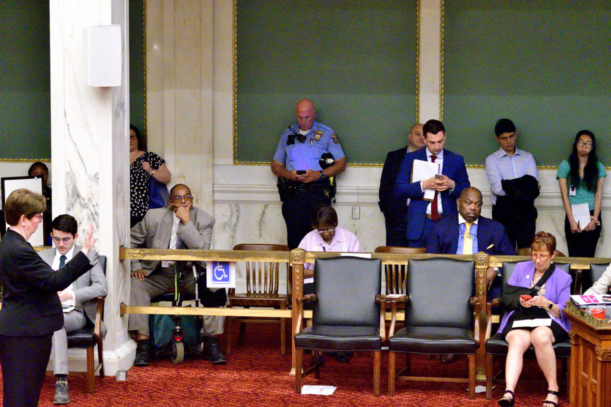 A police officer checks a mobile phone during public testimony by community members and activists on controversial social media posts by officers of the Philadelphia Police Department