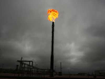 A pillar blasts a plume of fire into a cloudy sky, natural gas, fracking