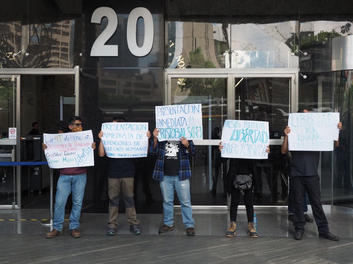 Demonstrators hold up signs outside the doors to a building