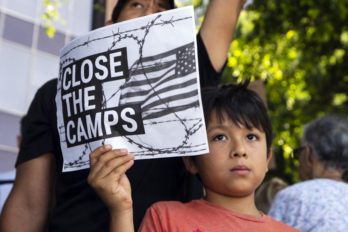 A child holds a sign during a Close The Camps protest against migrant detention centers.